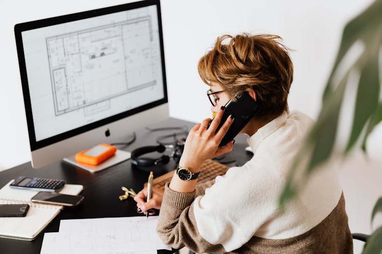 Serious Woman Having Conversation On Smartphone And Taking Notes