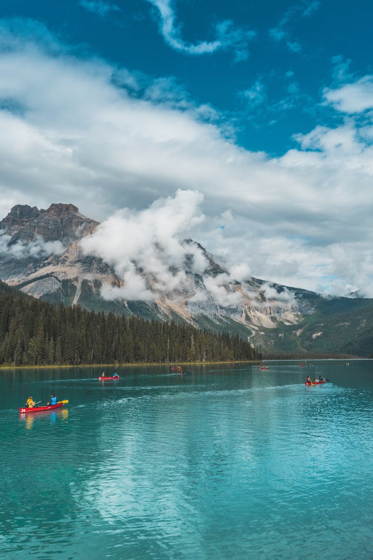 Photo Of People Riding Kayak On Lake Across Mountain