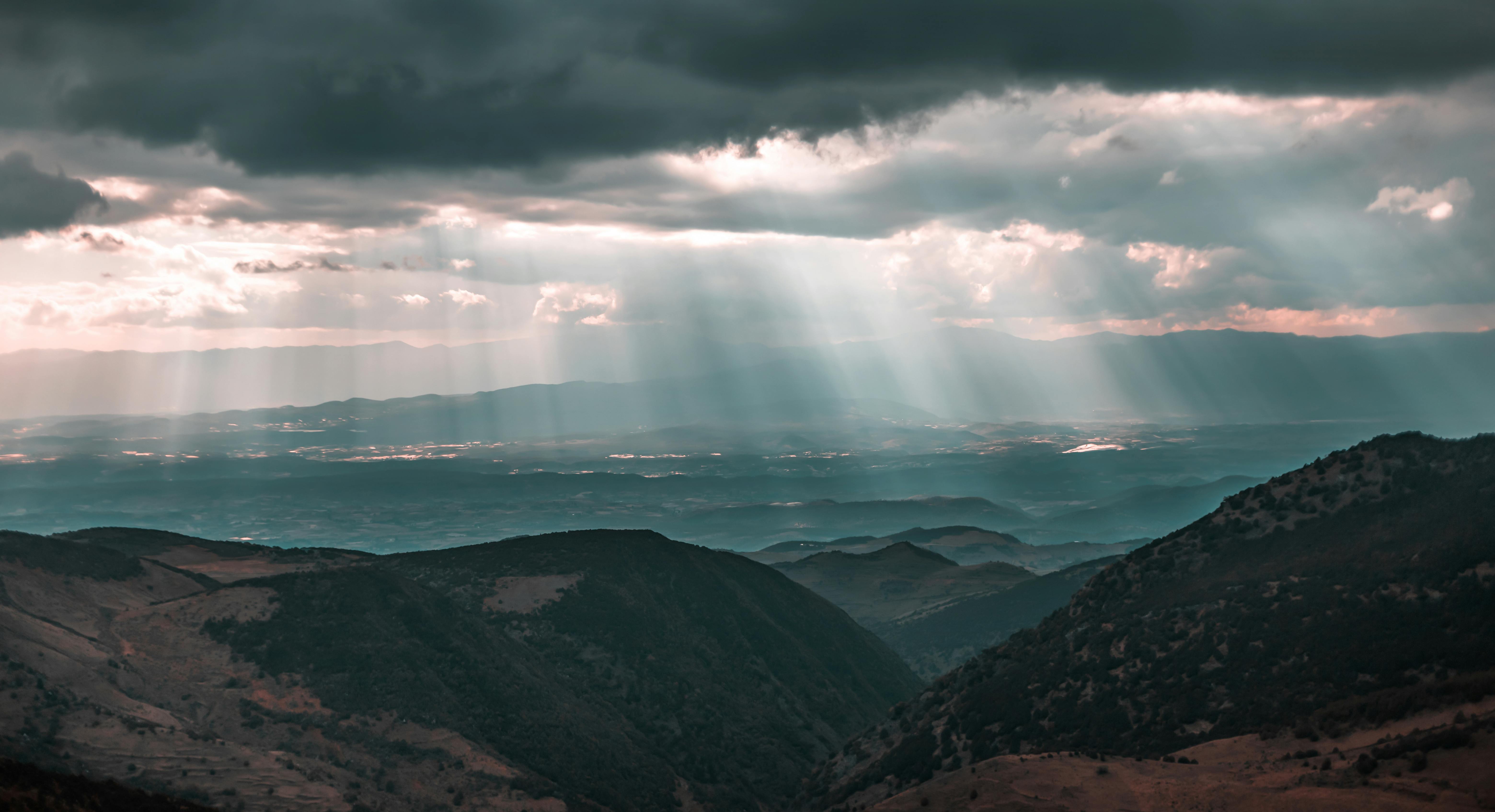 Beautiful landscape of mountains with sunbeams through dramatic clouds, capturing a serene and majestic view.