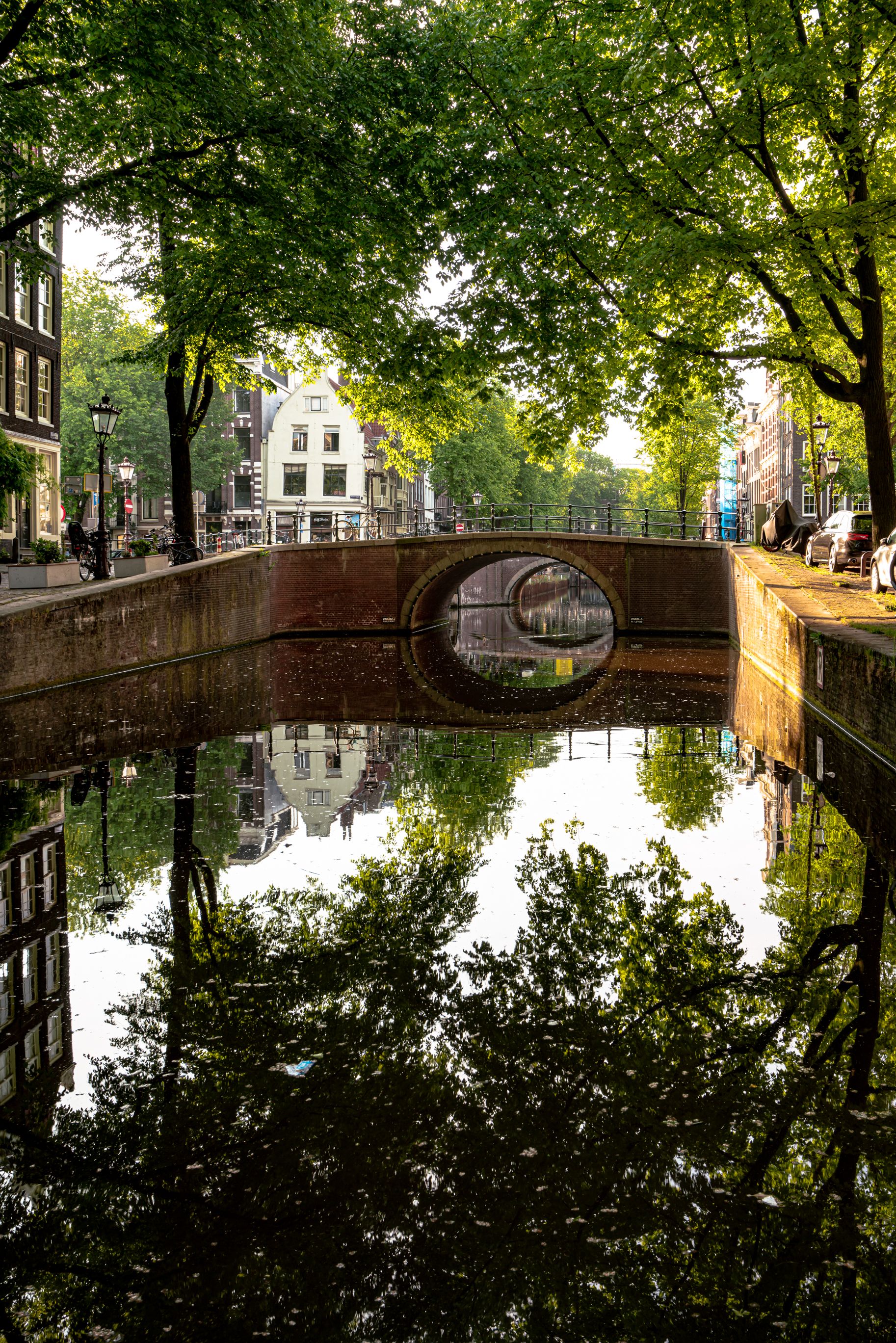 Arched bridge over an Amsterdam canal with tree reflections, a common first-date walking route