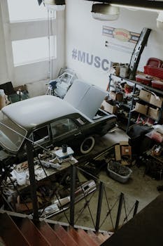 一辆老爷车正在凌乱的汽车车间里用工具和设备进行维修