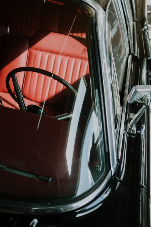 Free Close-up view of a classic car interior featuring red leather seats and a black steering wheel. Stock Photo