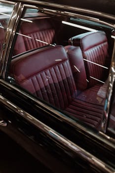 Close-up view of a classic car interior featuring red leather seats and chrome details.