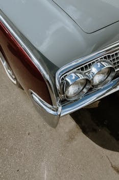 Close-up of a vintage car's chrome headlights and body, showcasing classic automotive style.