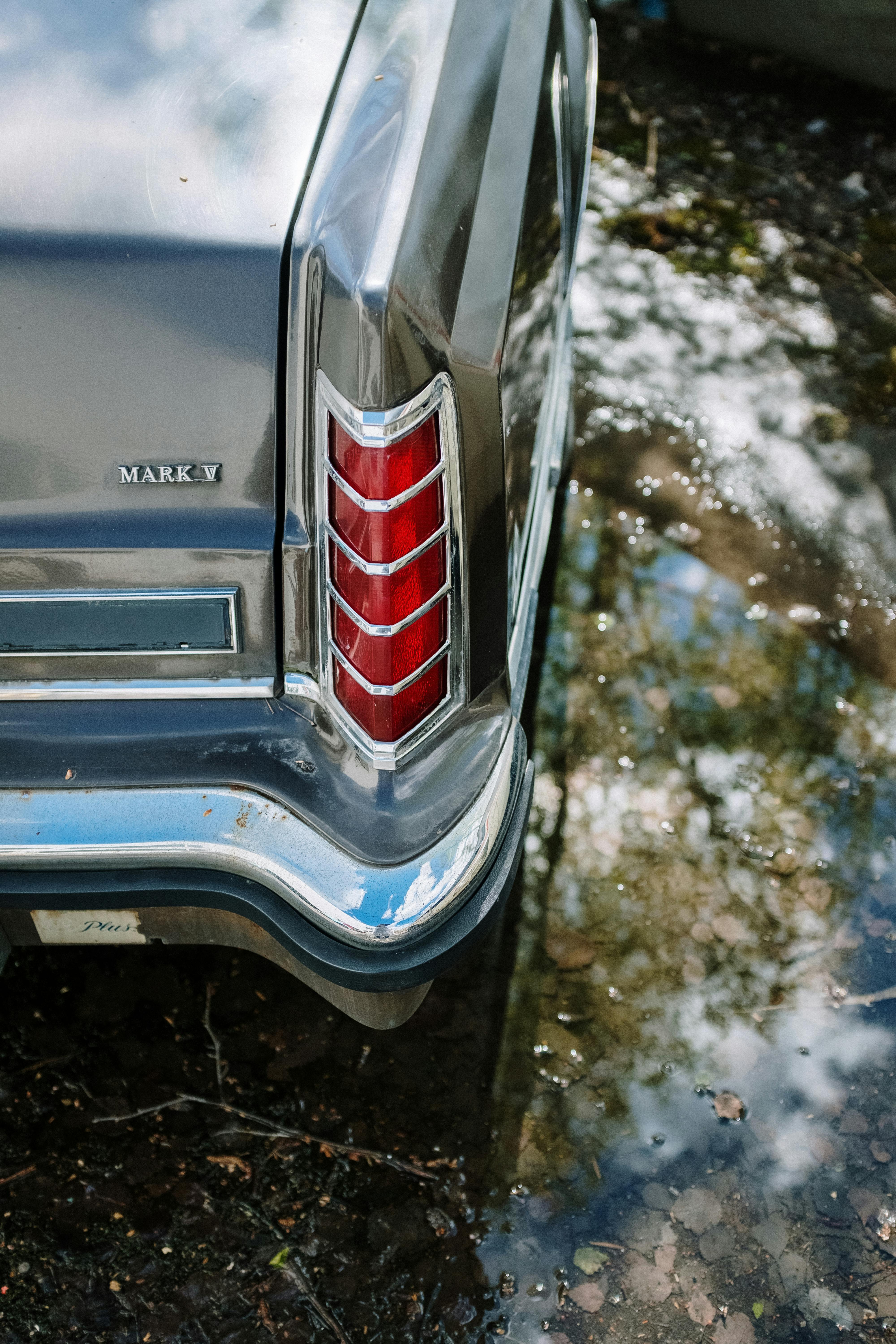 经典汽车尾灯特写倒映在水面上，尽显复古风格