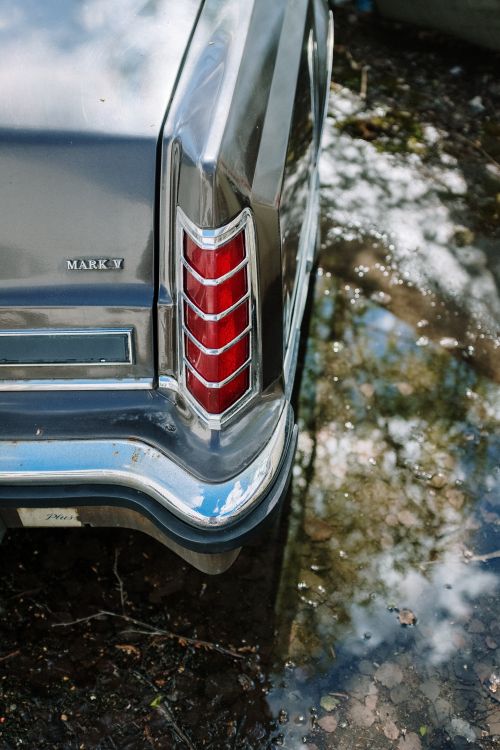 Free Close-up of a classic car's tail light with reflections on water, showcasing vintage style. Stock Photo