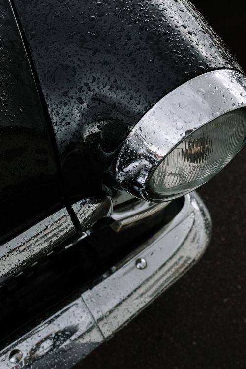 Free Detailed shot of a vintage car headlight covered in rain droplets, showcasing classic car aesthetics. Stock Photo