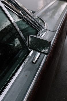 一辆老爷车的特写，雨滴挂在侧镜和车窗上，尽显经典优雅
