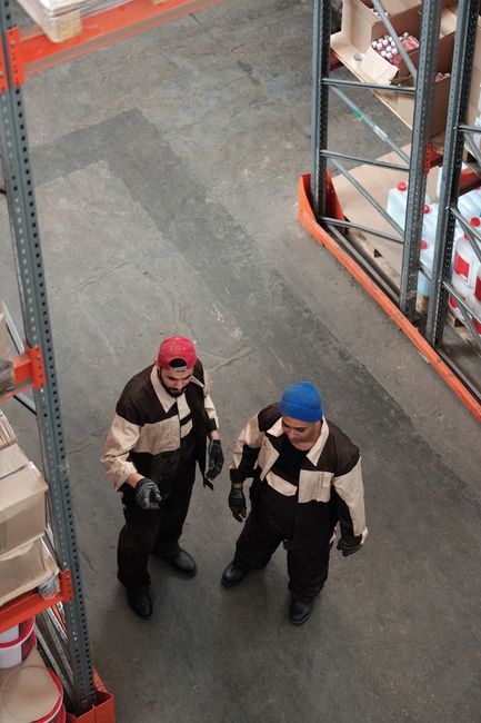 Two workers in a warehouse discussing logistics in an industrial setting Two workers in a warehouse discussing logistics in an industrial setting