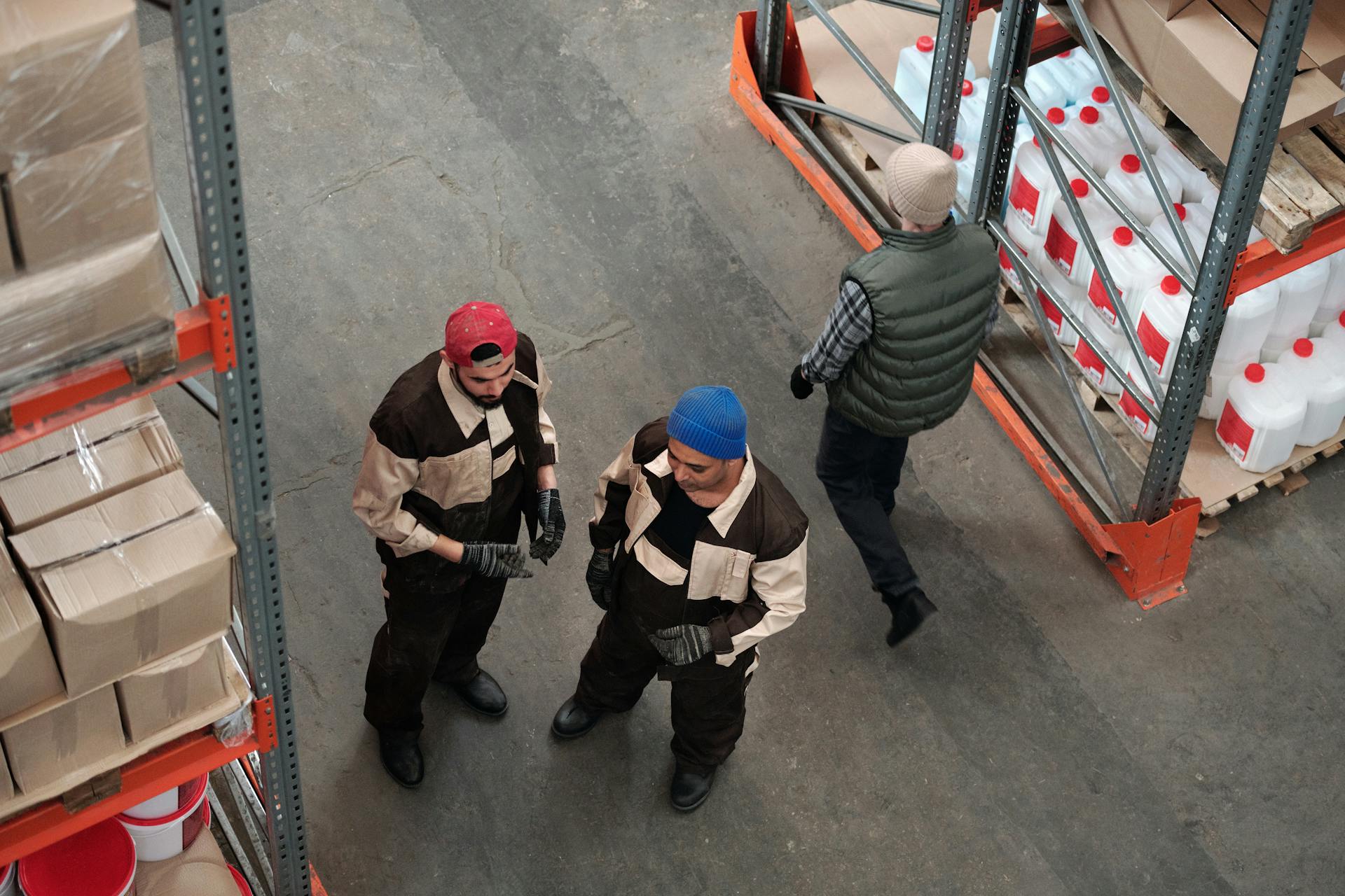 High angle view of warehouse workers organizing boxes and containers on storage shelves.