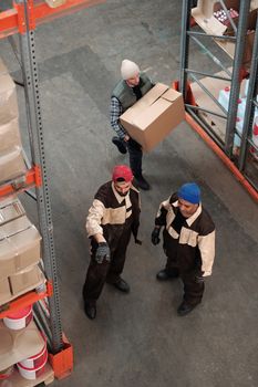 Team of workers managing inventory in a warehouse, emphasizing logistics and teamwork.