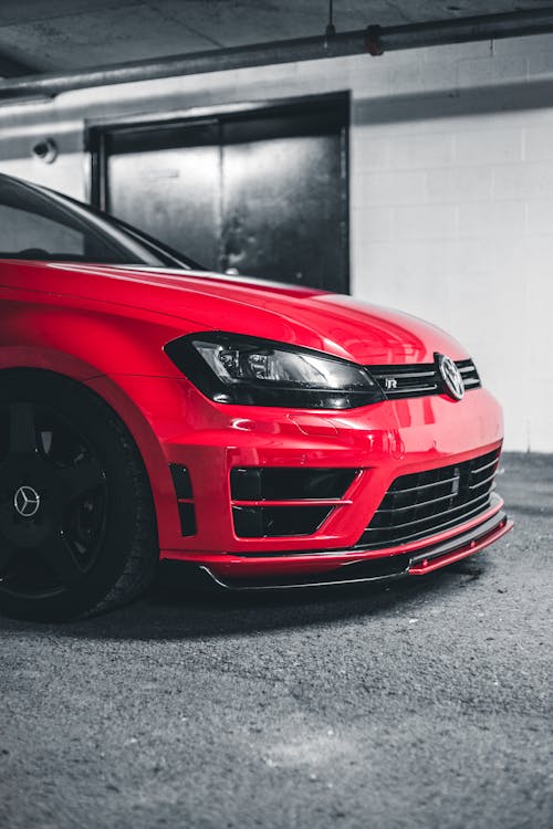 Detail of tuned modern red car parked in clean garage illuminated by bright light