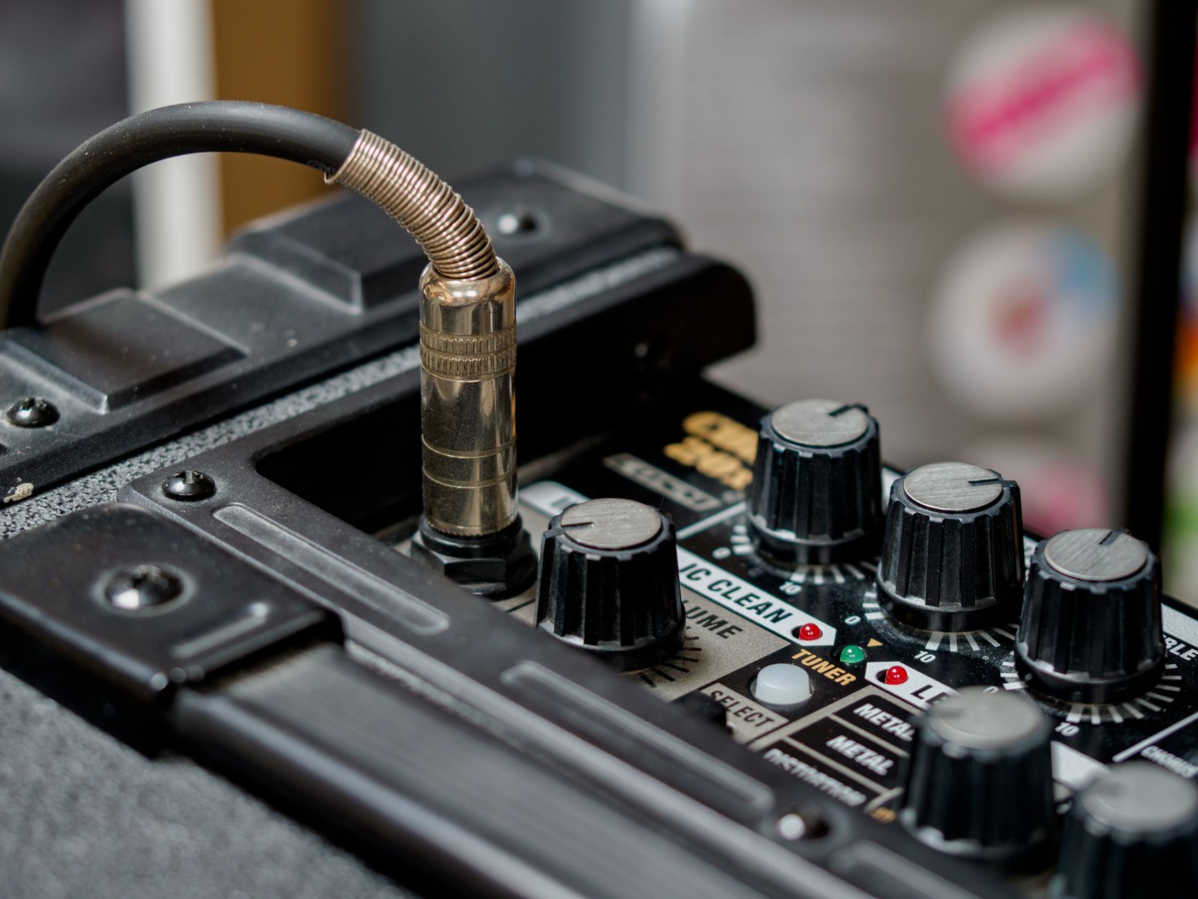 Detailed view of audio equipment featuring cable connection and control knobs.