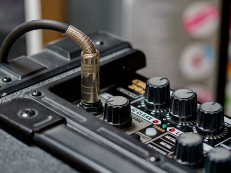 Detailed view of audio equipment featuring cable connection and control knobs.