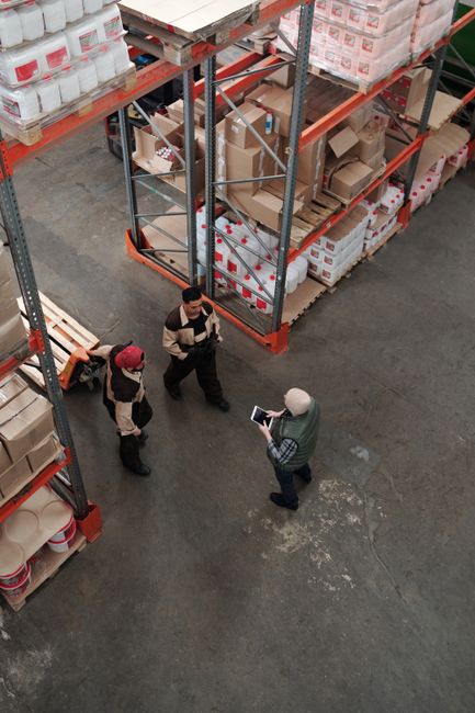 Workers discuss logistics in a busy warehouse setting, enhancing teamwork and efficiency. Workers discuss logistics in a busy warehouse setting, enhancing teamwork and efficiency.