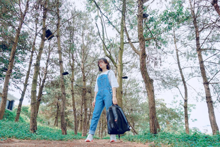 A Woman Wearing Dungarees Holding Her Backpack