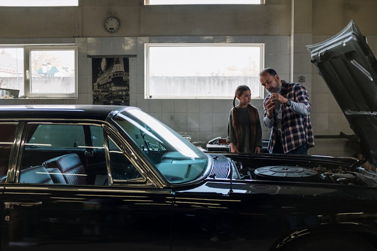 A Mechanic Talking To His Little Daughter At An Auto Repair Shop