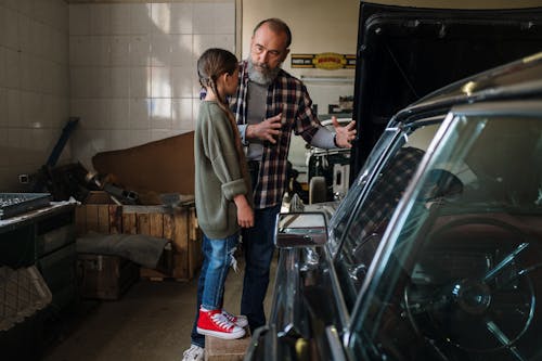 A Man Talking to his Daughter while Standing by the Car in a Garage 