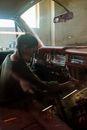孩子坐在一辆老爷车里，调整着仪表板上可见的辫子和焦点控制装置