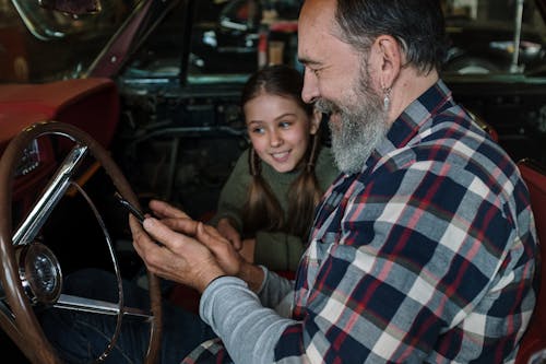Free Father and Daughter Looking at the Phone while Sitting in the Car  Stock Photo
