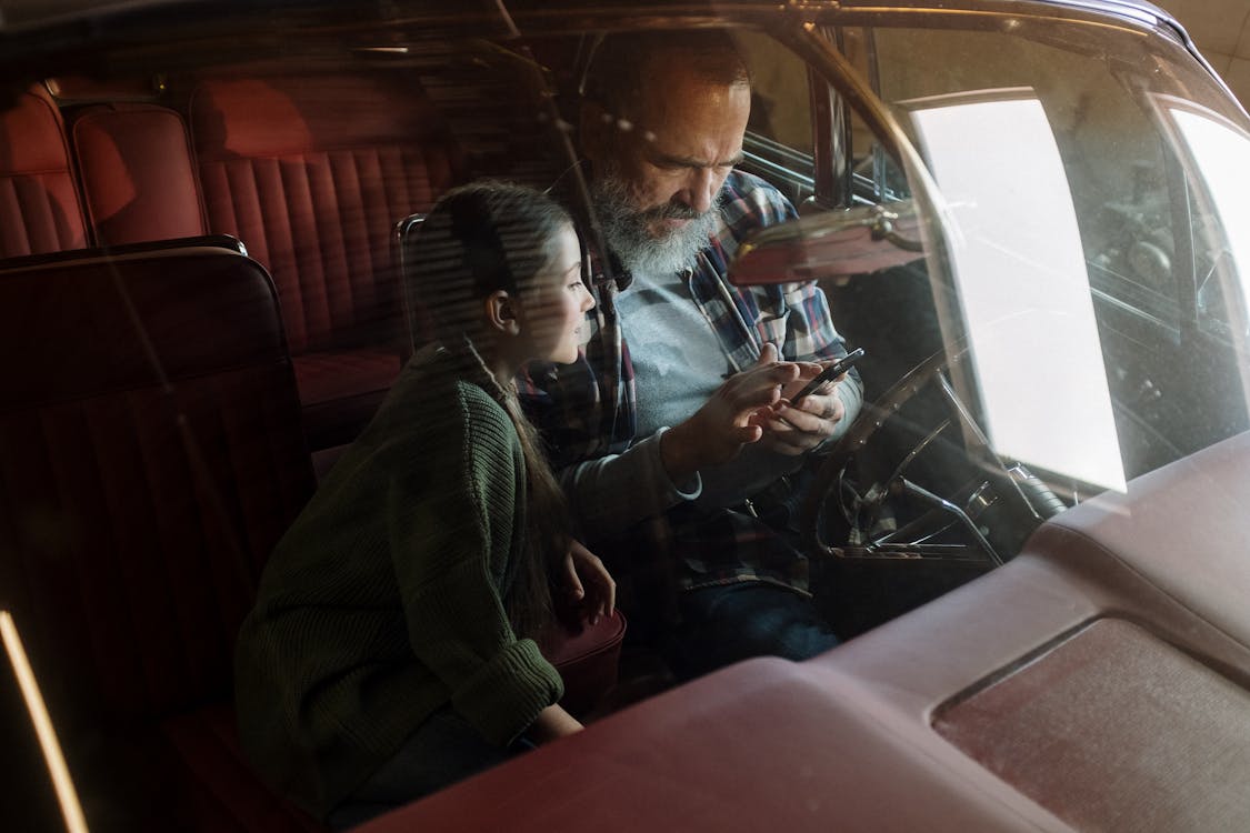 Free Father and Daughter Looking at the Phone while Sitting in the Car Stock Photo