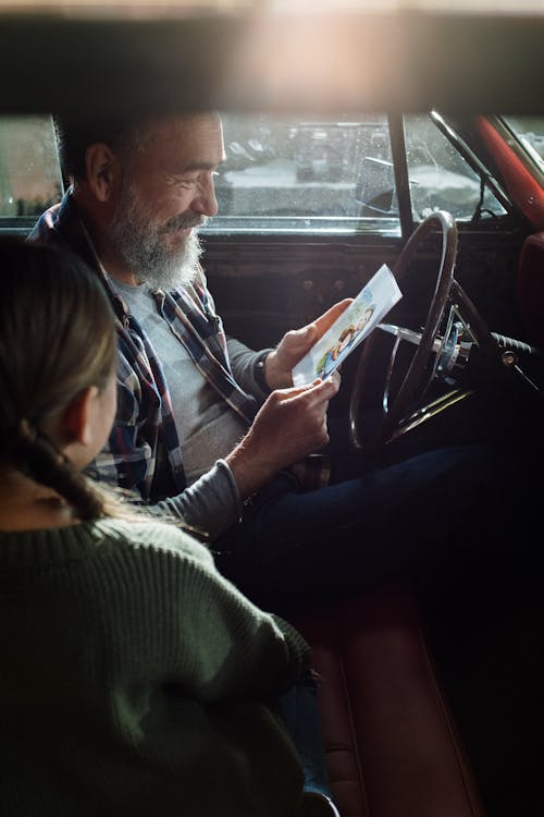 Free A Man Looking at a Greeting Card while Sitting in the Car with his Daughter Stock Photo