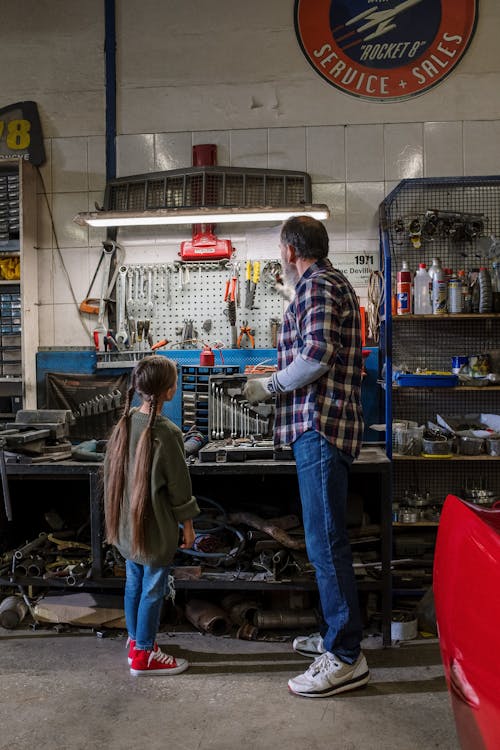 Free Back View of a Mechanic and his Daughter Looking at Tools in the Garage Stock Photo
