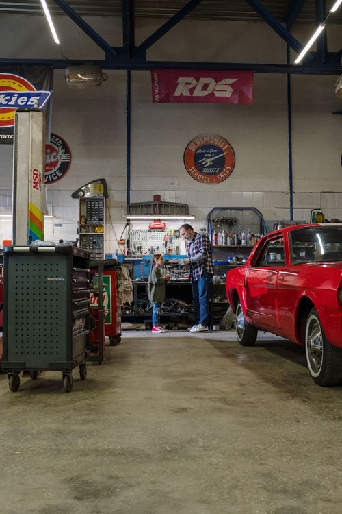 Free Father and daughter spending quality time in a garage, repairing a car together. Stock Photo