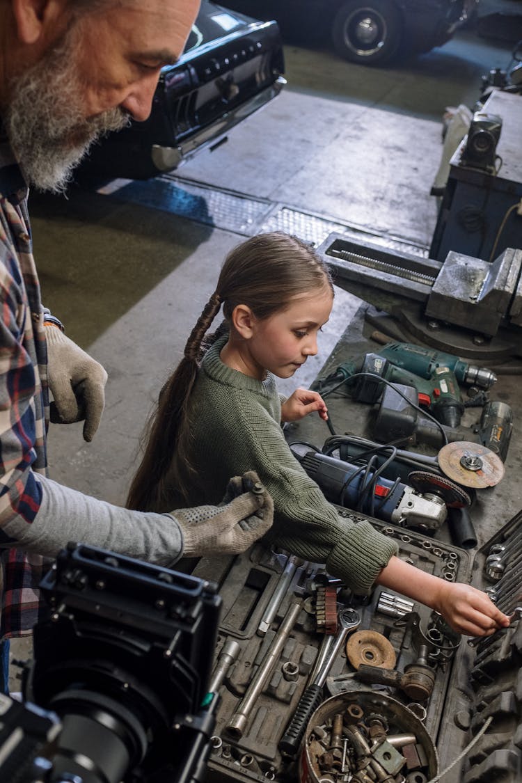 A Girl And Her Father Looking At Tools In A Garage