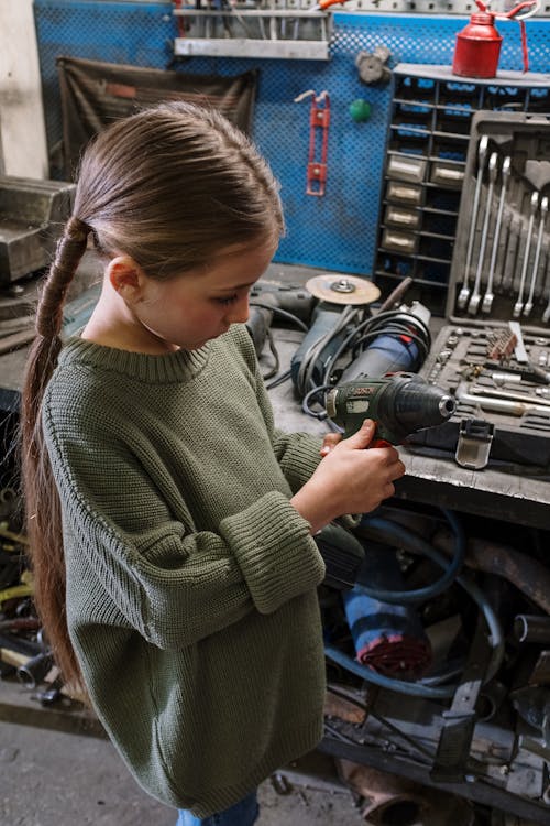Woman in Green Sweater Holding Black and Gray Corded Power Tool