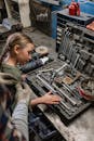 Woman in Gray Jacket Holding Black Metal Tool