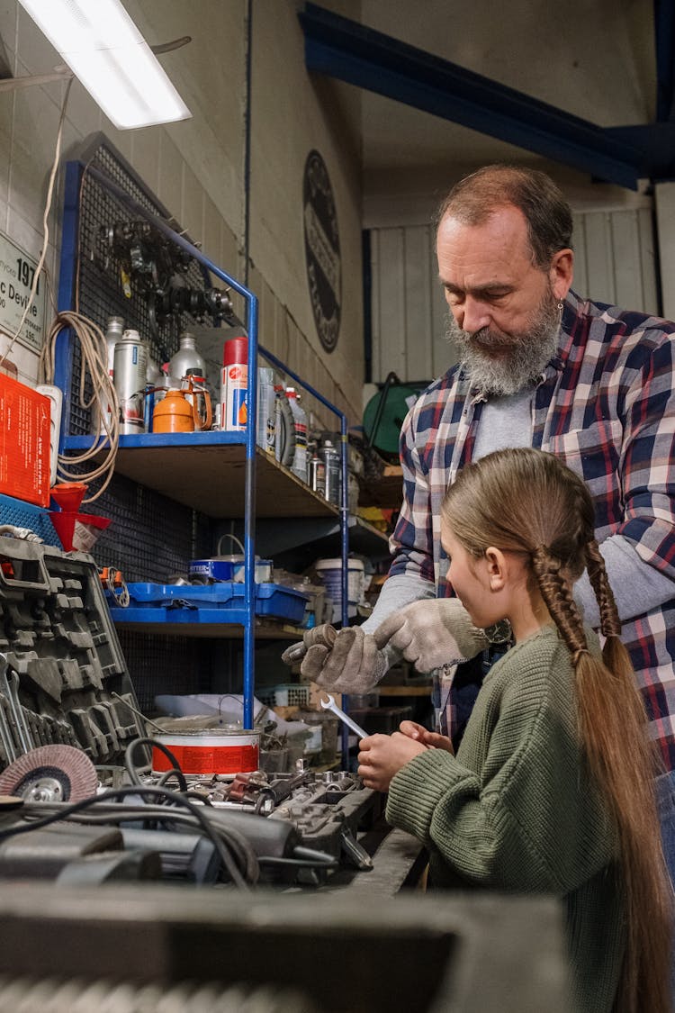 A Little Girl And Her Dad Looking At Tools In A Garage