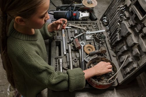 Boy in Green Sweater Holding Gray Metal Tool