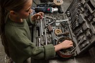 一名年轻女孩在车库车间里检查各种工具和设备，展现出好奇心和动手学习的精神