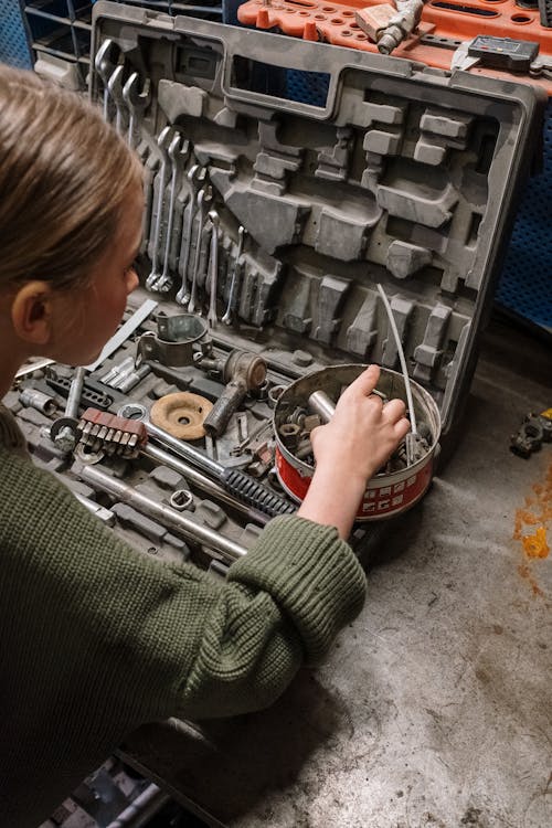 Woman in Green Sweater Holding Gray Metal Tool