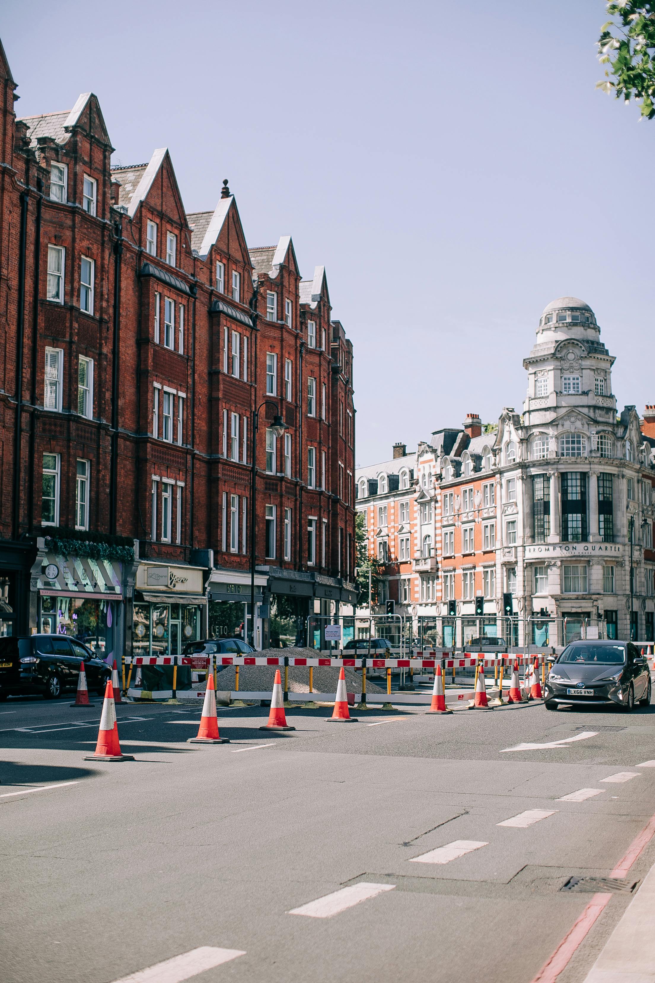 Charming street view showcasing historic London architecture with red brick buildings and traffic cones.
