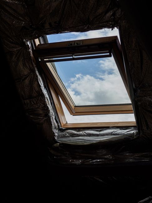 Photo by Brett Jordan on Pexels A wooden attic window opens to reveal a clear blue sky and fluffy white clouds.