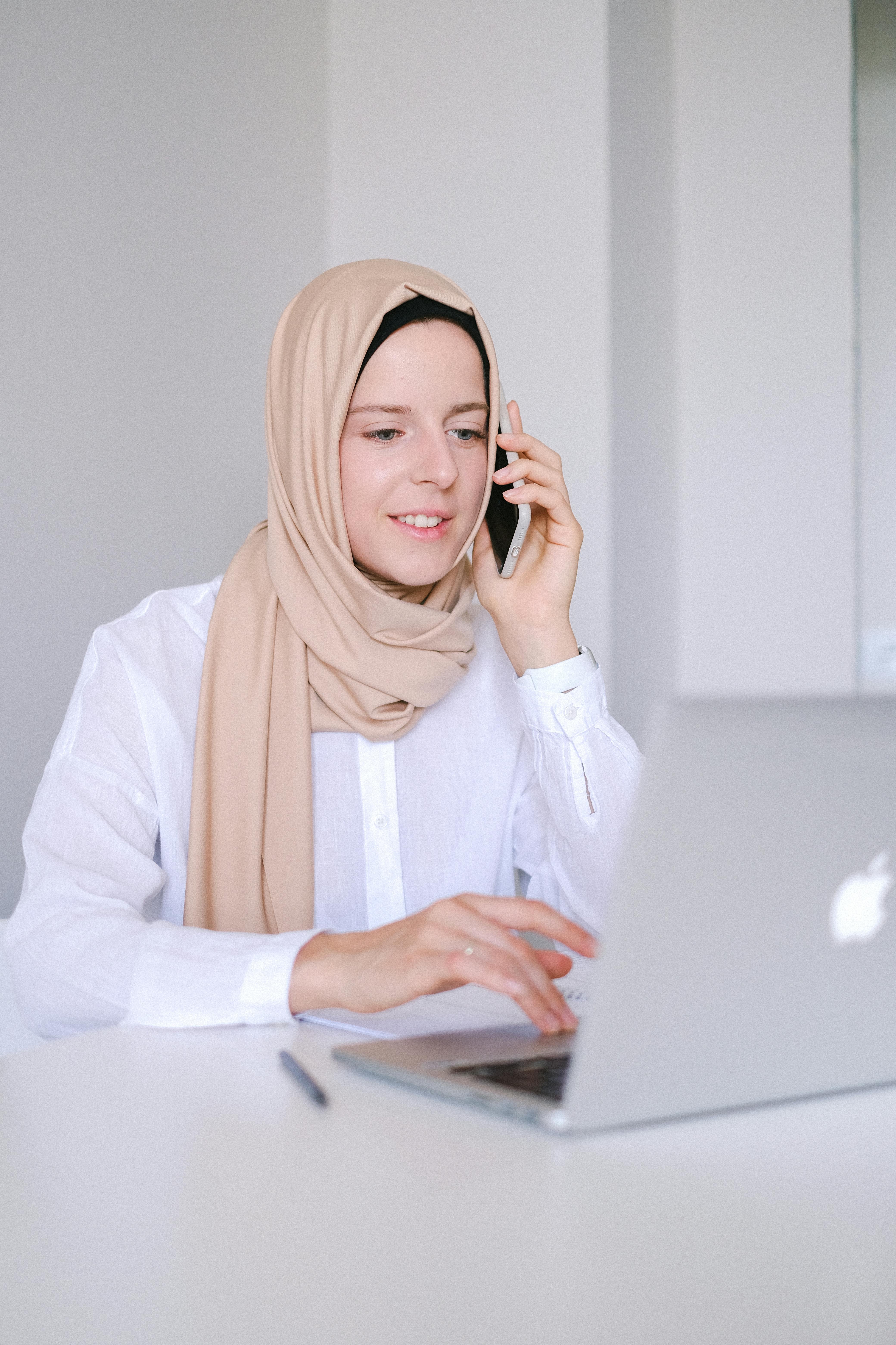woman in white long sleeve shirt and orange hijab using macbook