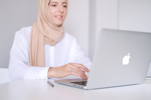 Woman in White Long Sleeve Shirt Using Macbook Air