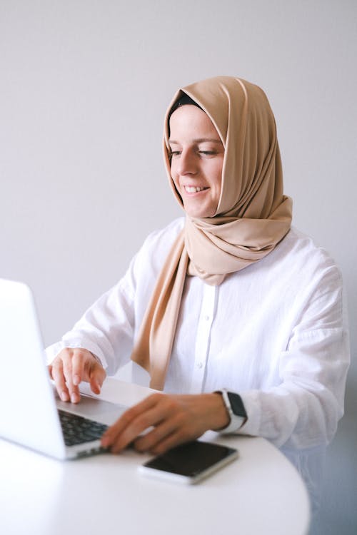 Woman in White Long Sleeve Shirt Using Macbook Pro