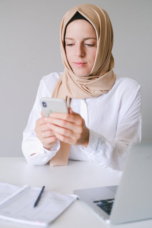 Free Woman in White Long Sleeve Shirt Holding White Smartphone Stock Photo