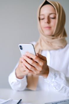 A Muslim woman in a hijab using a smartphone, illustrating modern communication.