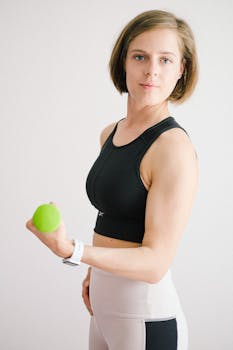 Strong woman exercising indoors with a green dumbbell, promoting healthy lifestyle.