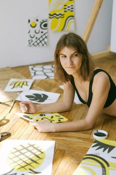 在创意工作室的地板上，一名妇女躺着画抽象艺术