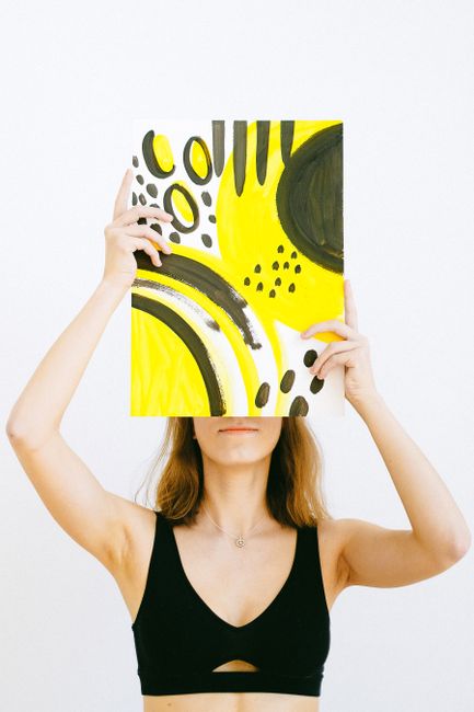 A woman poses with a bold abstract painting in a studio setting.