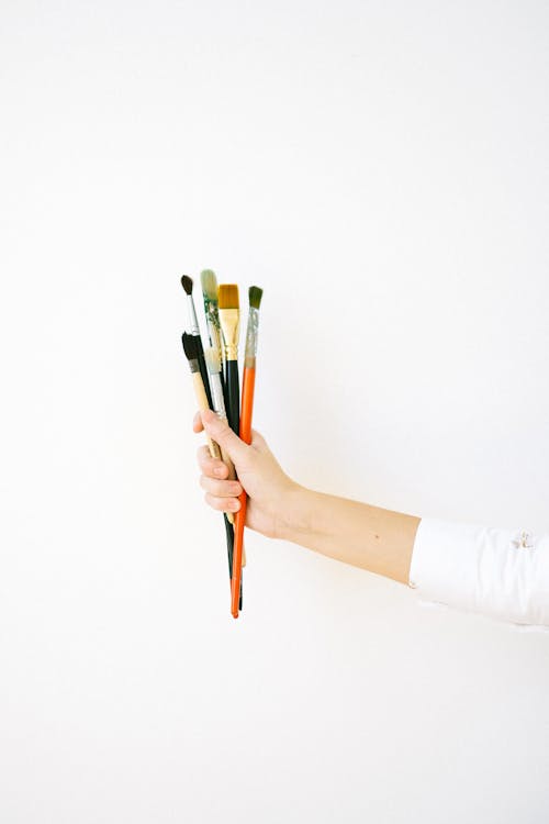 Person Holding Paint Brushes