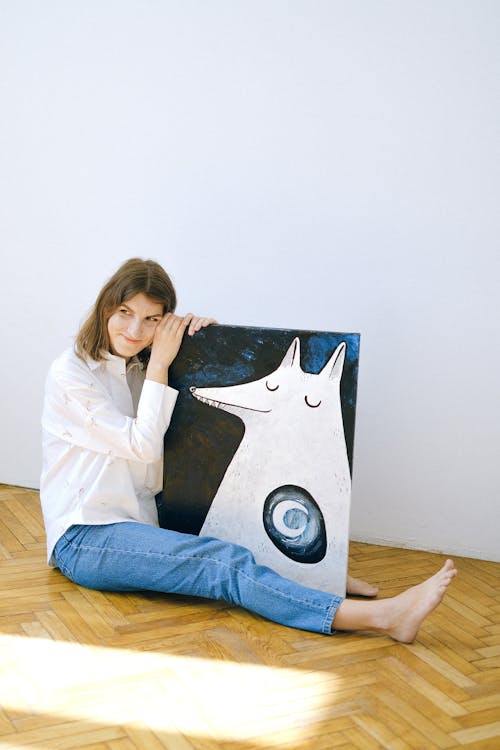 Woman in White Long Sleeve Shirt and Blue Denim Jeans Sitting Floor