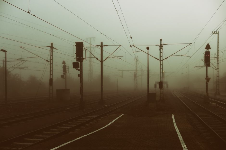 Mist-covered railway lines at a station, evoking a sense of mystery and journey.