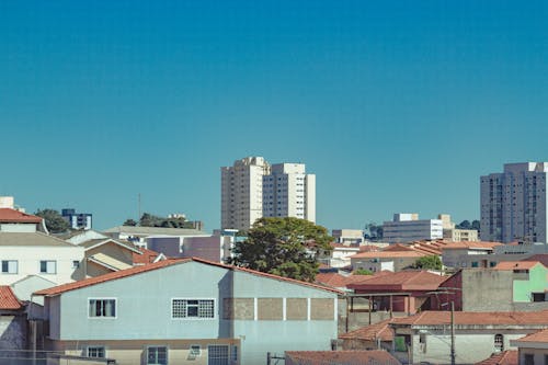 Cityscape of modern district with high residential buildings and low rise houses against blue cloudless sky in summer day