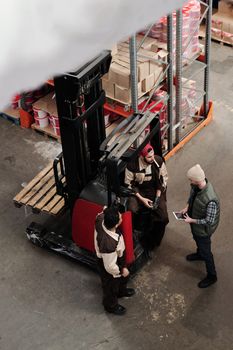 Overhead view of warehouse workers having a meeting with forklift equipment. Collaborative workplace scenario.